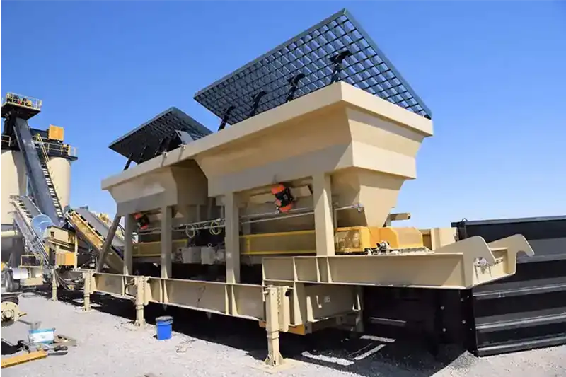 Aggregate feed bins and conveyor system at a portable material processing plant